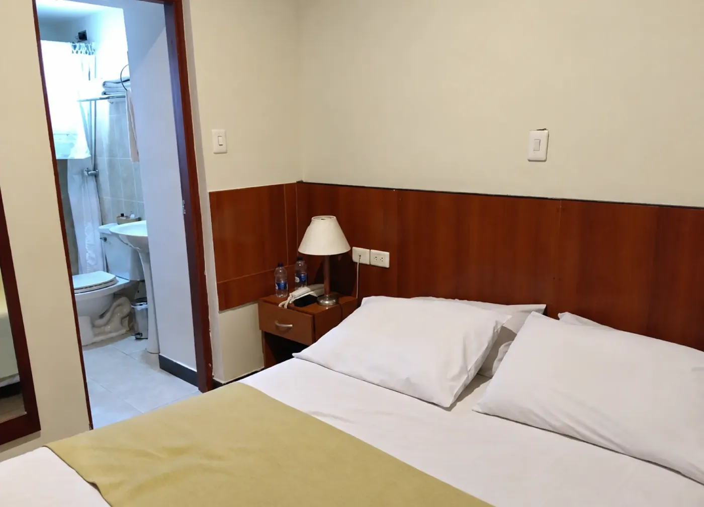 Cama doble junto a la puerta de un baño privado